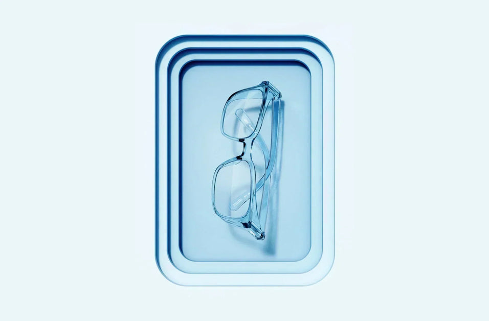 Blue Stoggles safety glasses resting on a matching tray against a pale blue background, showcasing stylish protective eyewear.