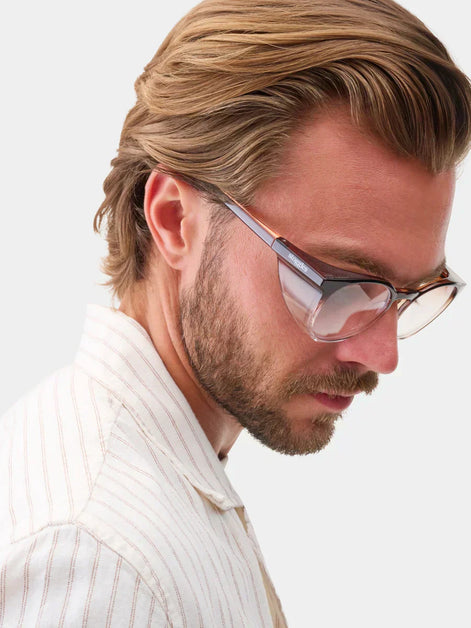 Man wearing Stoggles Dimmers safety glasses while looking down in a striped shirt.