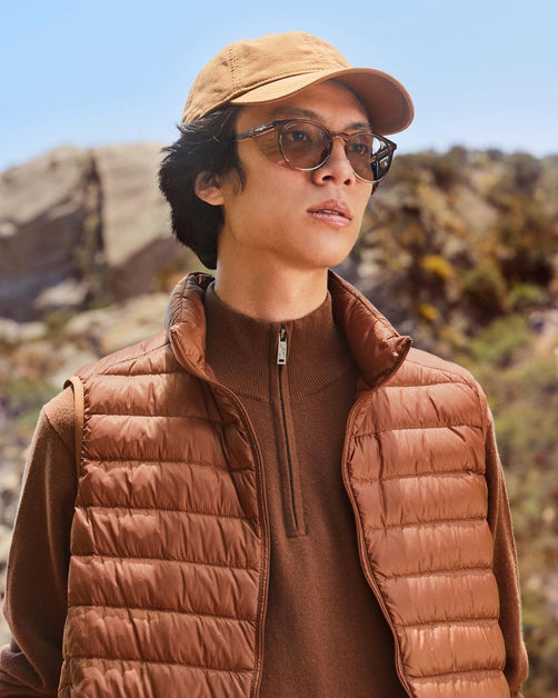 Man with a square-shaped face wearing a brown shirt, jacket, cap, and matching Stoggles glasses.