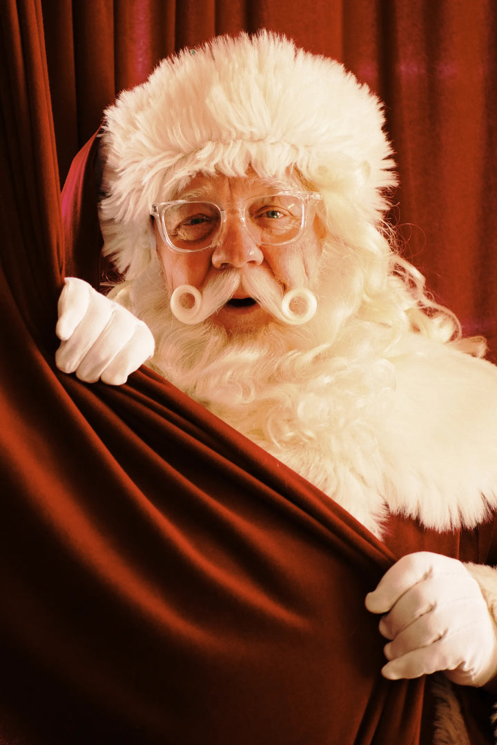 Santa Clause wearing Stoggles behind a red curtain