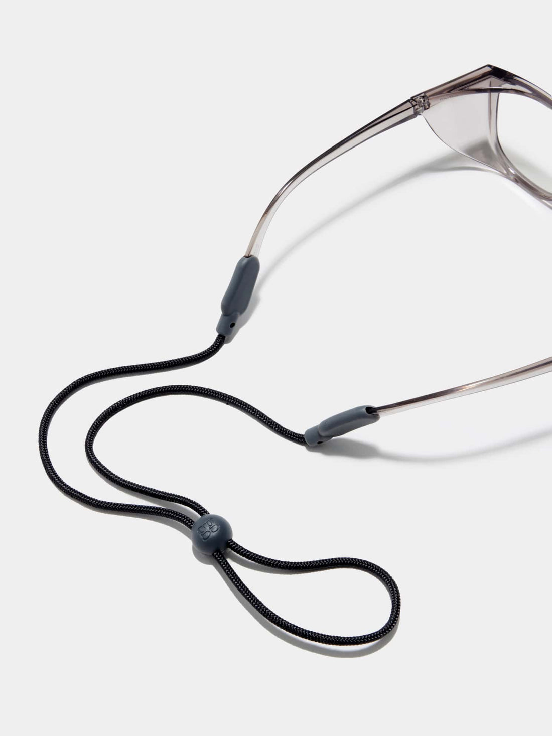 A shot of Stoggles sunglasses with a black neck cord resting on a white background, emphasizing functionality.
